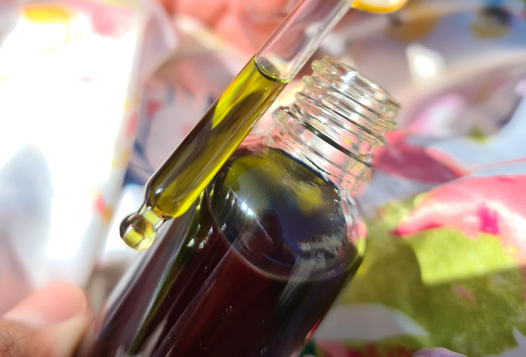 A close up of a small bottle dropper filled with Bobinsana Tincture, a beautifully green colour liquid, held in front of the full bottle.